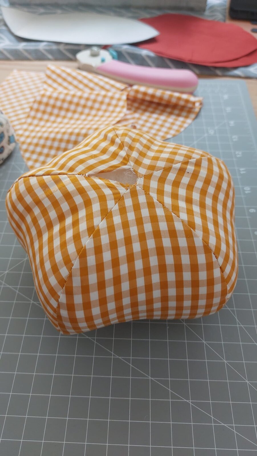 A gingham pumpkin being filled with stuffing
